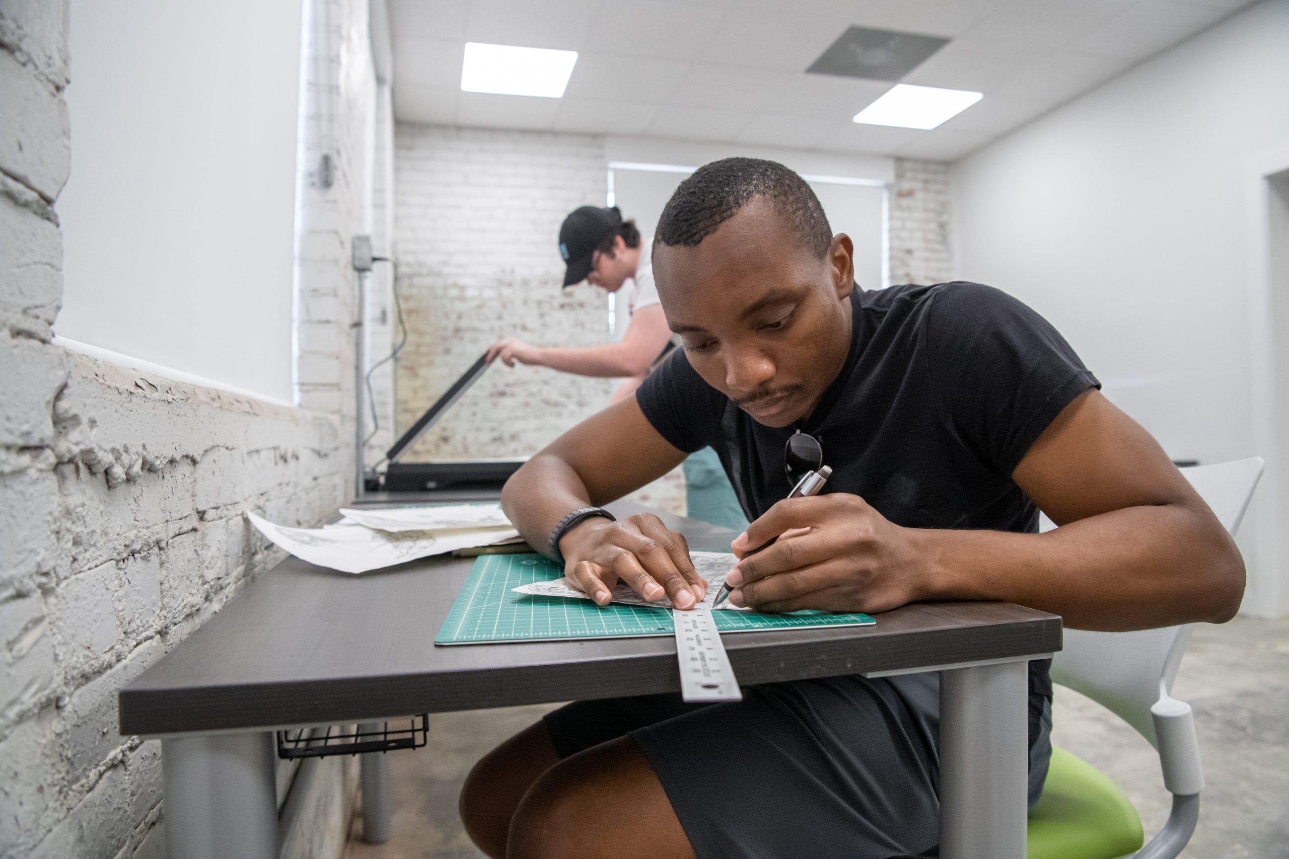 Student sitting at a table, drawing in the art lab.